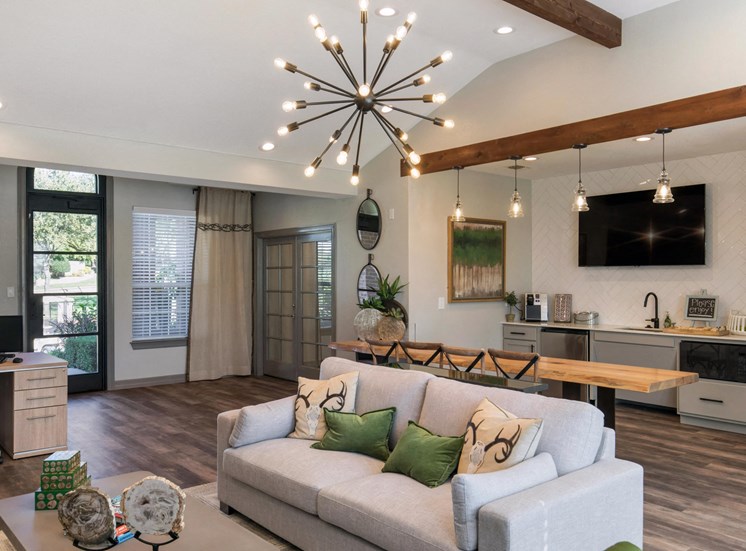 Clubhouse interior with modern decor and lighting, light gray couch, and wooden accents